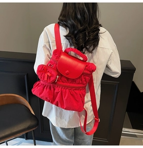 Detail of red pleated backpack fabric with heart charm and secure magnetic closure