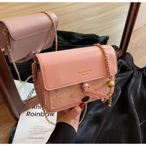 Pink crossbody bag detail showing litchi grain leather texture and floral embossed patterns