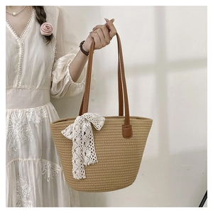 Detail of hand-woven tote bag with white lace bow and brown faux leather handles
