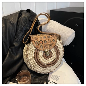 Detail of round straw bag with cork flap featuring bohemian geometric pattern and bronze lock