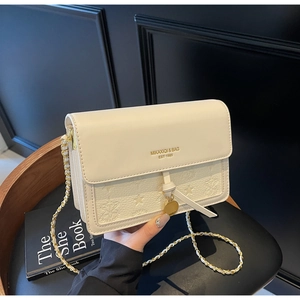 Detail of white leather bag with star embossed texture and golden metal chain strap