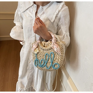 Detail of straw woven bucket bag with blue hello embroidery and floral scarf handle