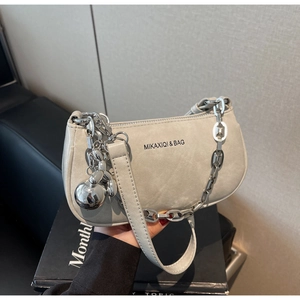 Détail du sac bandoulière gris avec chaîne argentée et pendentif métallique sphérique