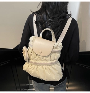 Detailed back view of a pleated beige backpack with a matching small hanging pouch charm