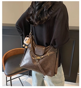 Detail of dark brown leather tote showing fashion embossed logo and metallic side eyelets