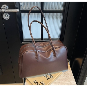 Detail of dark brown lychee pattern leather tote bag on marble surface with accessories