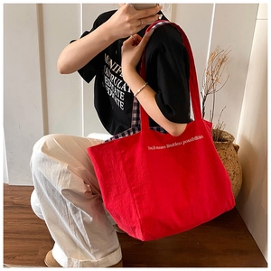 Detail view of red canvas tote bag with white inspirational text and checkered lining