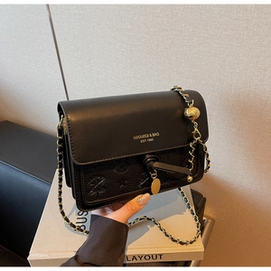 Detail of black leather crossbody bag with golden chain strap and embossed palm pattern