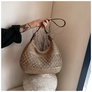 Detail of hand-woven straw tote with white hollow mesh pattern and adjustable leather strap