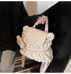 Detail of off-white pleated backpack featuring a matching mini pouch and ruffled handle