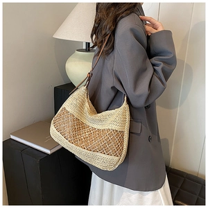 Detail of hollow-out straw woven tote bag with contrast stitching and leather strap