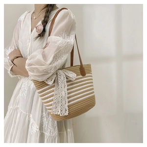 Detail of woven tote bag with khaki stripes and large white lace bow accent