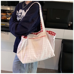 Detail of canvas tote bag showing red youth embroidery and red checkered inner lining
