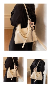 Detail of a creamy white faux leather tote bag with elegant charms and adjustable straps