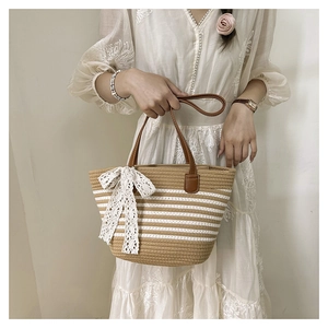 Close-up of woven straw tote bag with white stripes and brown leather handles