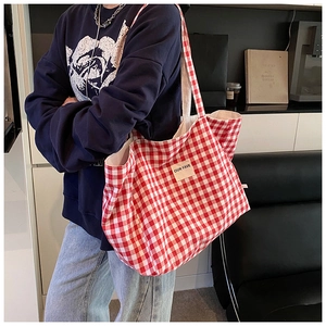 Detail of red gingham tote bag with long shoulder strap and OUR FAVE woven label