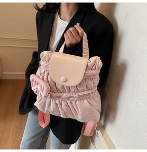 Detail of pink pleated backpack with leather flap and cute bow purse charm accessory