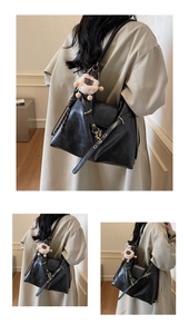 Detail of a black leather tote with a plush sheep charm and vintage metal hardware accents
