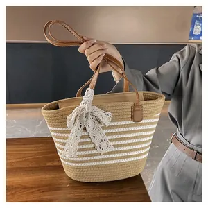 Detail of woven tote bag with white lace bow and brown leather handle for beach vacations