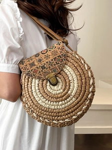 Bohemian round straw crossbody bag with floral cork lid shown on a model side view