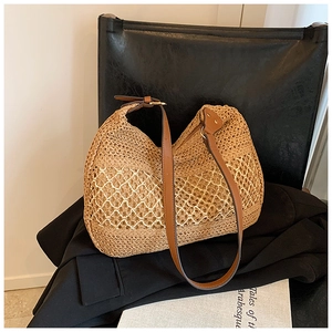 Detail of hand-woven straw tote with hollow mesh pattern and premium brown leather strap