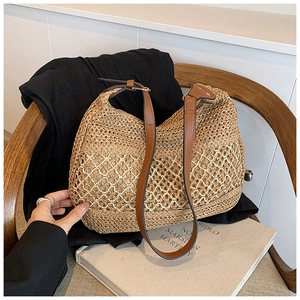Detail of hollow woven straw tote bag with adjustable brown leather shoulder strap