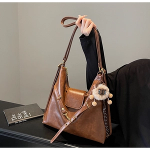 Macro view of vintage brown leather tote bag texture with plush charm and buckle straps