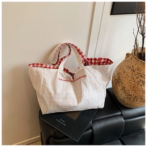 Close-up of canvas tote bag showing red gingham lining and youth embroidery detail