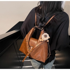 Detail of vintage brown leather backpack with plush sheep charm and adjustable metal buckle