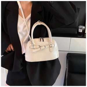 Detail of cream white shell-shaped bag with dual round handles and adjustable strap