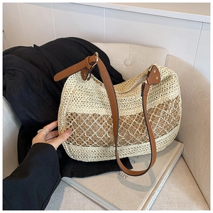 Detail of hollow woven straw tote bag with brown leather straps on a casual seat