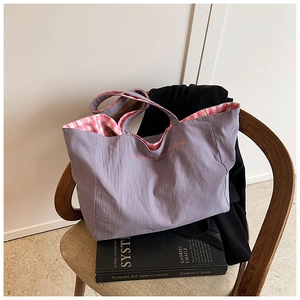 Detail of light purple canvas tote bag with pink embroidery and checkered lining