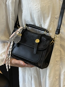 Chic black patchwork leather handbag with tennis racket charm and gold buckle detail