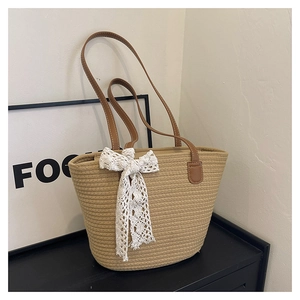 Detail of hand-woven tote bag with elegant white lace bow and brown leather straps