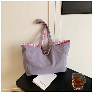 Close-up of purple canvas tote bag with pink embroidery and checkered lining detail