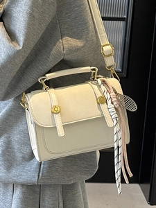 Chic cream leather square crossbody bag with gold buckles and decorative scarf detail