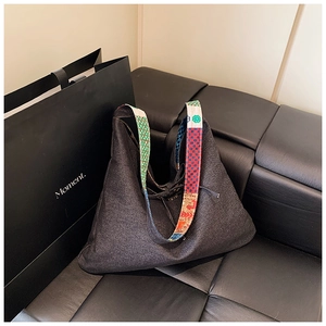 Close-up of bohemian patchwork tote bag with colorful geometric strap on leather sofa