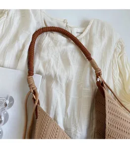 Detailed close-up of the woven shoulder strap and metal ring on a khaki tote bag