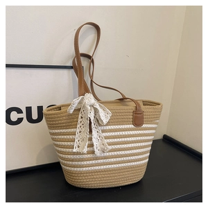 Detail of striped woven tote bag featuring brown leather straps and lace bow charm
