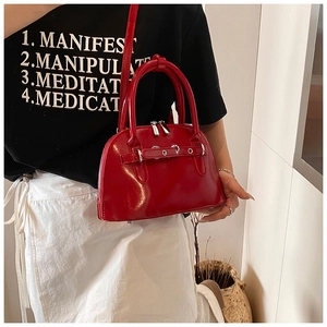 Detail of red glossy patent leather shell bag with silver hardware and dual handles