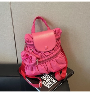 Detail view of pink pleated backpack with ruffle design and small bow charm on black leather