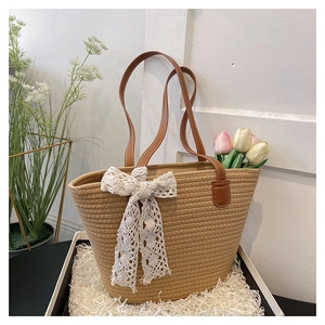 Close-up of woven straw tote bag featuring a white lace bow in a gift box packaging