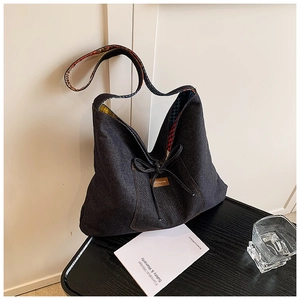 Close-up of bohemian denim tote bag with decorative bow and leather brand label