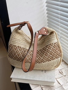 Chic hollow straw woven tote bag with brown leather strap in natural sunlight
