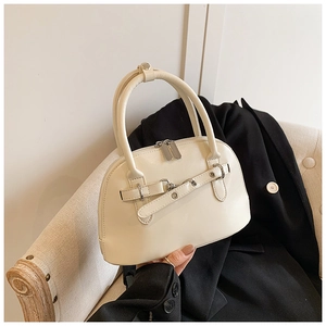 Detail of off-white crossbody shell bag with metal dual zippers and round handles