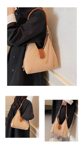 Detail of woven tote bag featuring beige chevron pattern and brown leather buckle strap