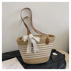 Detail of straw tote bag with beige stripes, lace bow, and brown faux leather straps