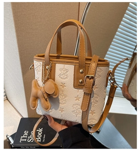 Gros plan détaillé du mini sac seau en cuir grainé blanc avec motifs d'étoiles gaufrés