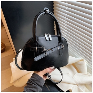 Close-up of shell-shaped black leather bag with silver buckle and sleek zipper detail