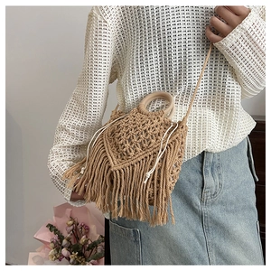 Detail of bohemian handmade woven bag with wooden handle and fringe tassels decoration